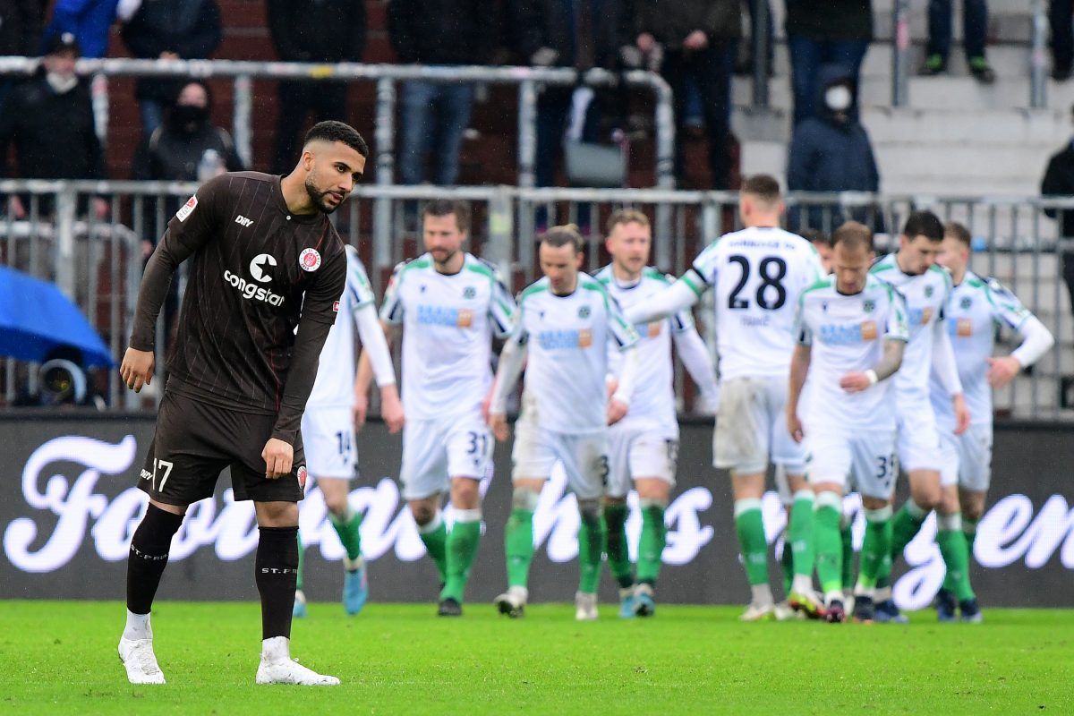 Daniel-Kofi Kyereh ist enttäuscht nach einem Gegentor des FC St. Pauli. Im Hintergrund feiern die Spieler von Hannover 96 den Treffer.