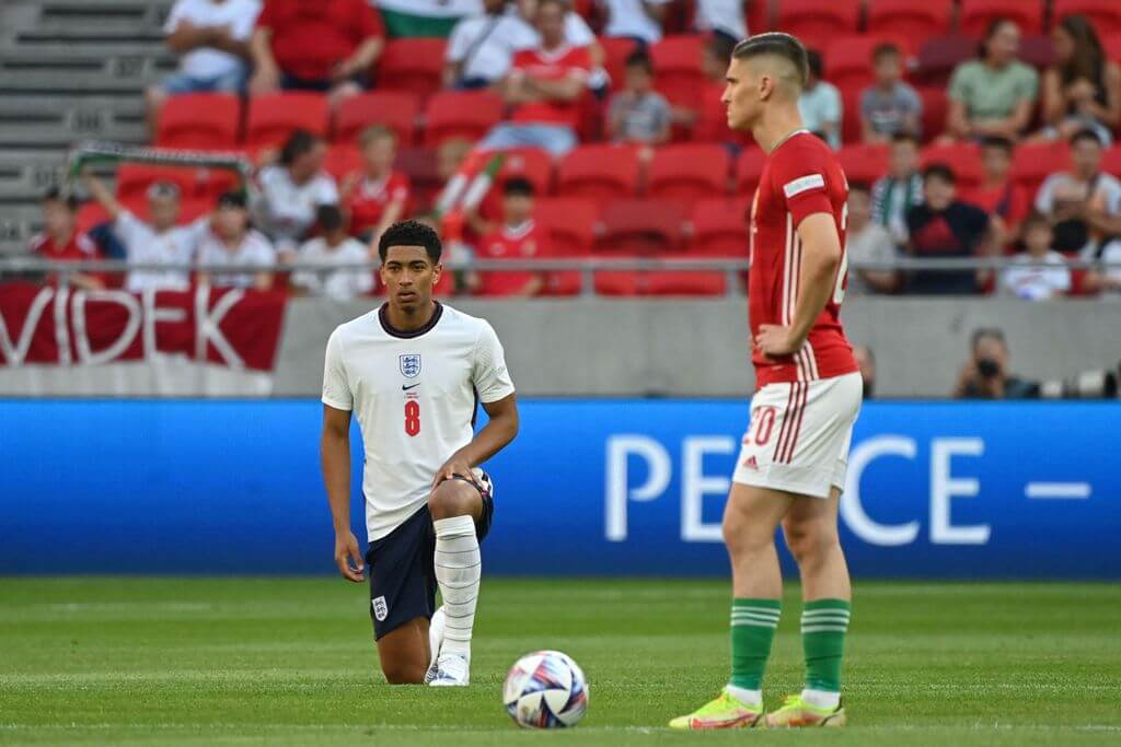 Der englische Nationalspieler Jude Bellingham geht vor dem Länderspiel in Ungarn aufs Knie. Neben ihm steht der ungarische Nationalspieler Roland Sallai.