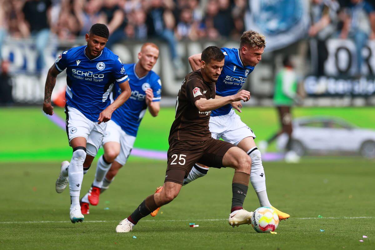 HAMBURG, GERMANY - APRIL 29: Adam Dzwigala of FC St. Pauli is challenged by Robin Hack of DSC Arminia Bielefeld during the Second Bundesliga match between FC St. Pauli and DSC Arminia Bielefeld at Millerntor Stadium on April 29, 2023 in Hamburg, Germany. (Photo by Martin Rose/Getty Images)