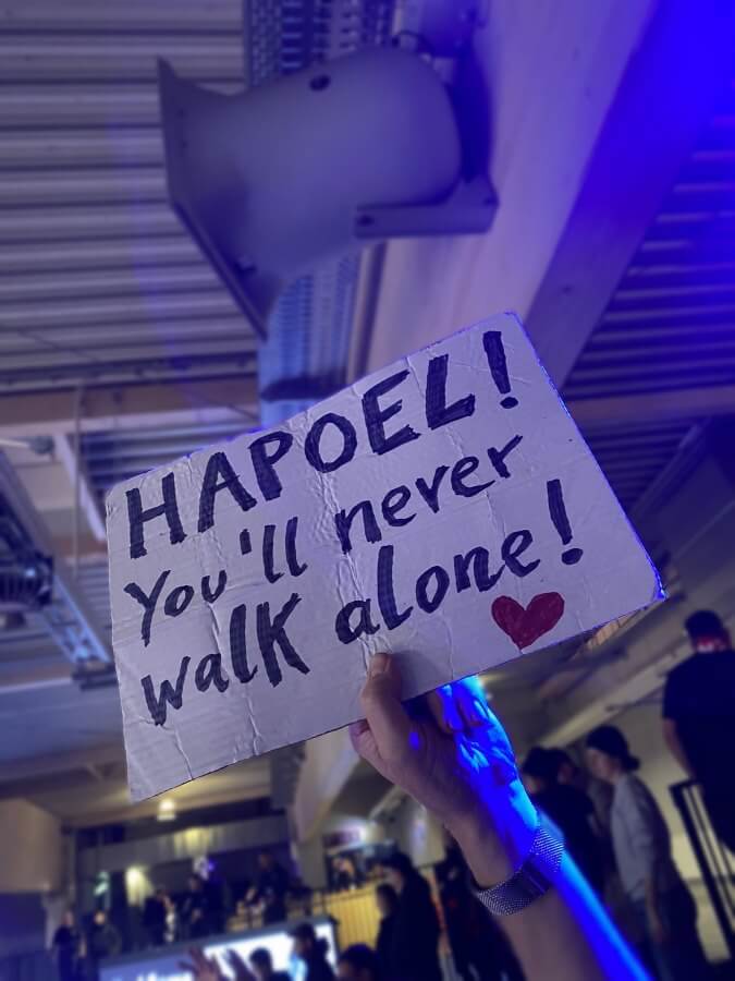 Pappschild mit der Aufschrift: 
"HAPOEL! You'll never walk alone!" und einem Herz.