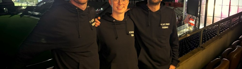 Mattes, Nelly und Jon stehen auf der Südkurve, mit dem Rücken zum Stadion. Hinter ihnen ist es dunkel, vom DOM und der Feldarena her ist aber Beleuchtung.