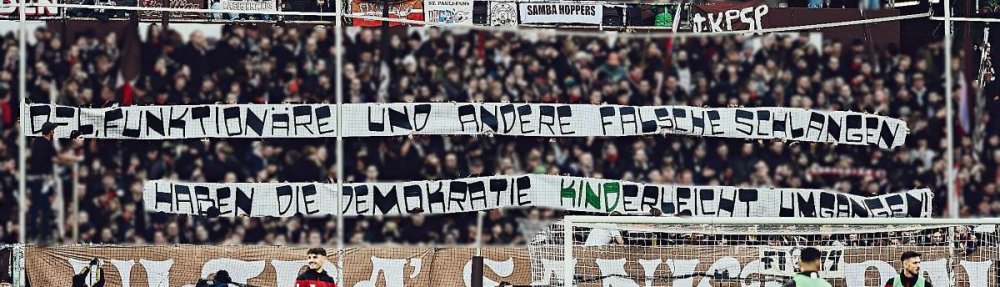 Tapeten in der Südkurve: "DFL, Funktionäre und andere falsche Schlangen - haben die Demokratie kinderleicht umgangen" Die Buchstaben "kind" sind in grün farblich hervorgehoben.