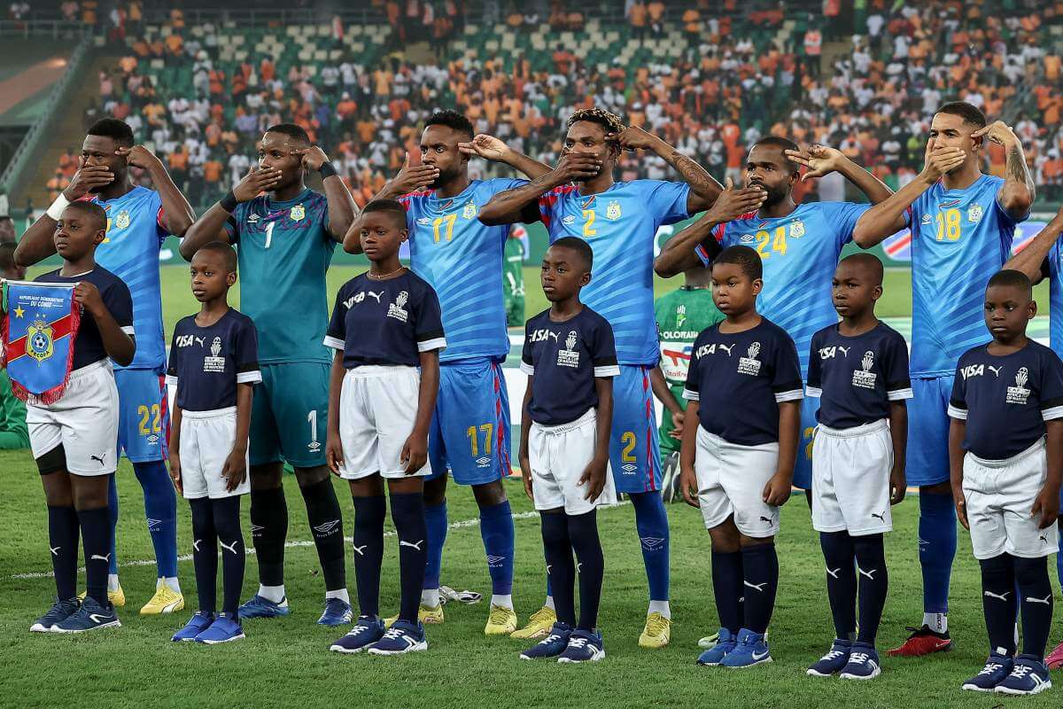 Vor dem Halbfinale beim Afrika Cup 2024 protestieren die Spieler der Demokratischen Republik Kongo bei der Nationalhymne gegen die Gewalt im eigenen Land. Dabei halten sie sich symbolisch eine Waffe an die Schläfe und den Mund zu.
