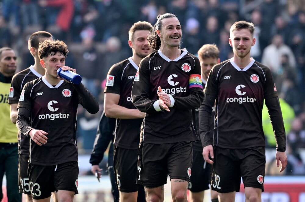 HAMBURG, GERMANY - MARCH 10: Philipp Treu, Jackson Irvine and Tjark Scheller of FC St. Pauli celebrate victory in the Second Bundesliga match between FC St. Pauli and Hertha BSC at the Millerntor Stadium on March 10, 2024 in Hamburg, Germany. (Photo by Oliver Hardt/Getty Images)