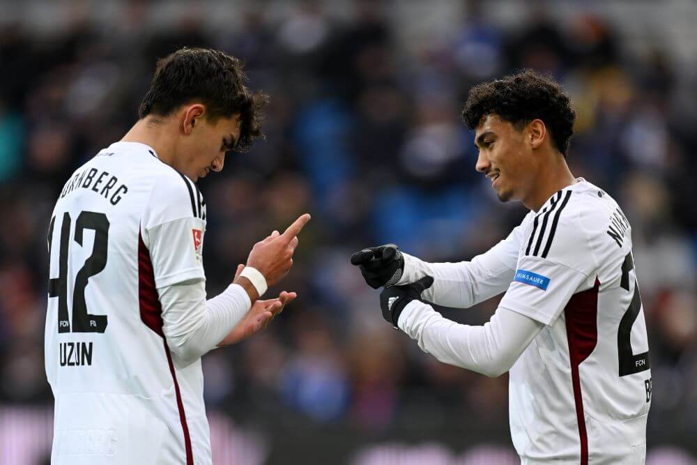 KARLSRUHE, GERMANY - NOVEMBER 26: Can Uzun of 1. FC Nuernberg (L) celebrates with teammate Nathaniel Brown after scoring the team's first goal during the Second Bundesliga match between Karlsruher SC and 1. FC Nürnberg at BBBank Wildpark on November 26, 2023 in Karlsruhe, Germany. (Photo by Matthias Hangst/Getty Images)