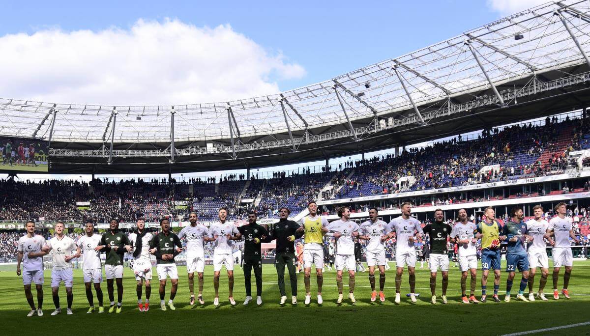 Das Team des FC St. Pauli eingehakt hüpfend vor der Gästekurve nach dem Sieg bei Hannover 96 am 21. April 2024.