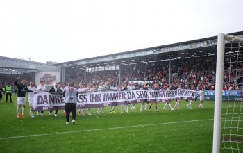 Die Spieler des FC St. Pauli feiern mit einem "Danke, dass Ihr immer da seid - morgen feiern wir mit Euch!"-Banner vor der Kurve die Meisterschaft der 2. Bundesliga. // Wiesbaden, Brita-Arena, 19. Mai 2024