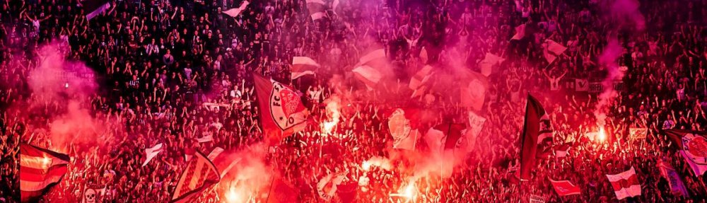 Der Oberrang des Gästeblocks wird von Fans des FC St. Pauli mit Pyrotechnik erleuchtet.