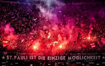 Der Oberrang des Gästeblocks wird von Fans des FC St. Pauli mit Pyrotechnik erleuchtet.