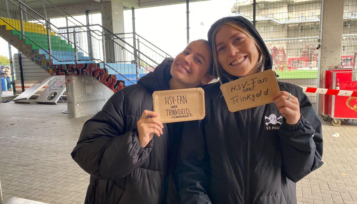 Lina und Merle mit "HSV-Fan oder Trinkgeld" Schildern zum Aufbessern der Teamkasse. 
