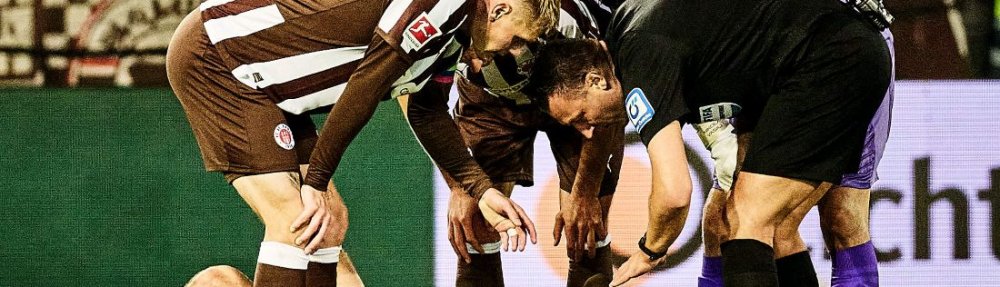 Hamburg, Deutschland, 19.10.2025, Millerntor-Stadion, Bundesliga, FC St. Pauli - TSG Hoffenheim James Sands (FC St. Pauli) liegt nach einem Sturz auf den Kopf am Boden, umringt vom Schiedsrichter und Mitspielern. Copyright: Stefan Groenveld