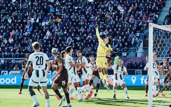 Der Keeper von Borussia Mönchengladbach versucht den Ball umgeben von anderen Spielern aus der Gefahrenzone zu fausten.