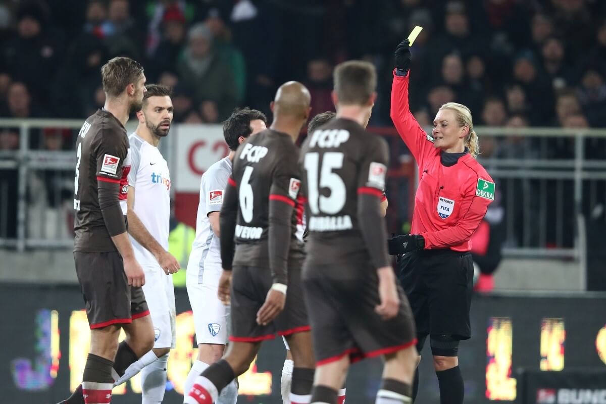 FIFA-Referee Bibiana Steinhaus präsentiert beim Spiel FC St. Pauli gegen VfL Bochum eine Gelbe Karte gegen Johannes Flum (verdeckt). // (c) Oliver Hardt/Bongarts/Getty Images via OneFootball