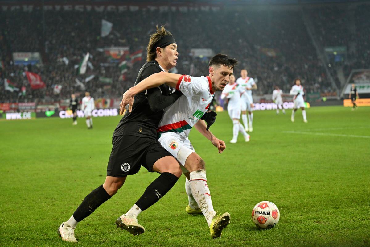AUGSBURG, GERMANY - JANUARY 31: Tomoya Ando of FC St.Pauli and Keven Schlotterbeck of FC Augsburg compete for the ball during the Bundesliga match between FC Augsburg and FC St. Pauli at WWK-Arena on January 31, 2026 in Augsburg, Germany. (Photo by Sebastian Widmann/Getty Images)