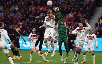LEVERKUSEN, GERMANY - FEBRUARY 14: Christian Kofane of Bayer 04 Leverkusen creates a headed chance under pressure from Karol Mets and Nikola Vasilj of FC St. Pauli during the Bundesliga match between Bayer 04 Leverkusen and FC St. Pauli at BayArena on February 14, 2026 in Leverkusen, Germany. (Photo by Christof Koepsel/Getty Images)