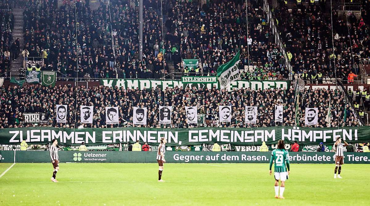 "Zusammen erinnern, gemeinsam kämpfen" - Banner im Gästeblock beim Spiel des FC St. Pauli gegen Werder Bremen am 22.02.2026 zum Gedenken an die Opfer des rechtsradikalen Anaschlags von Hanau im Februar 2020. Zusätzlich werden die Gesichter und Vornamen der zehn Opfer auf Doppelhaltern gezeigt. // (c) Stefan Groenveld