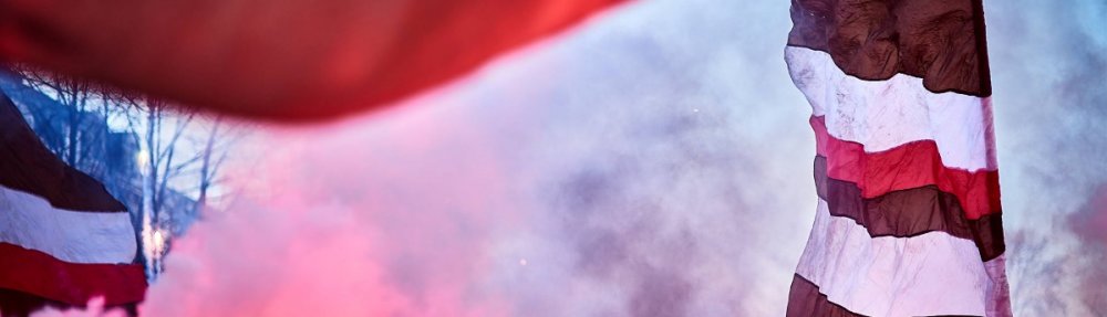 Busempfang des Teams durch die Fans des FC St. Pauli vor dem Spiel gegen den SC Freiburg. Pyrotechnik und braun-weiß-rote Fahnen. // (c) Stefan Groenveld