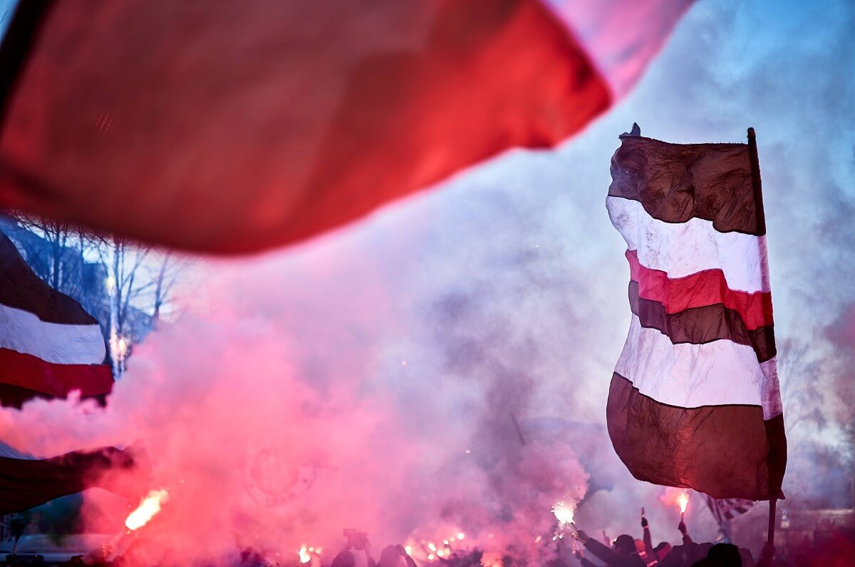 Busempfang des Teams durch die Fans des FC St. Pauli vor dem Spiel gegen den SC Freiburg. Pyrotechnik und braun-weiß-rote Fahnen. // (c) Stefan Groenveld