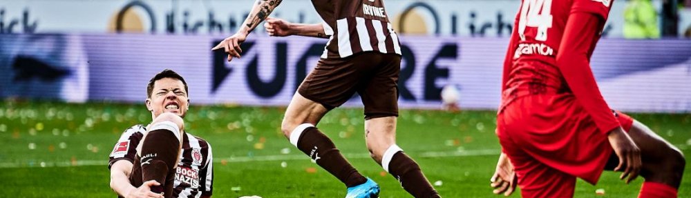 Hamburg, Deutschland, 22.03.2026, Fussball, Bundesliga, Millerntor-Stadion, FC St. Pauli - SC Freiburg Matthias Rasmussen hält sich nach einem Zweikampf das rechte Schienbein, Jackson Irvine ist auf dem Weg zum Schiedsrichter. Copyright: Stefan Groenveld