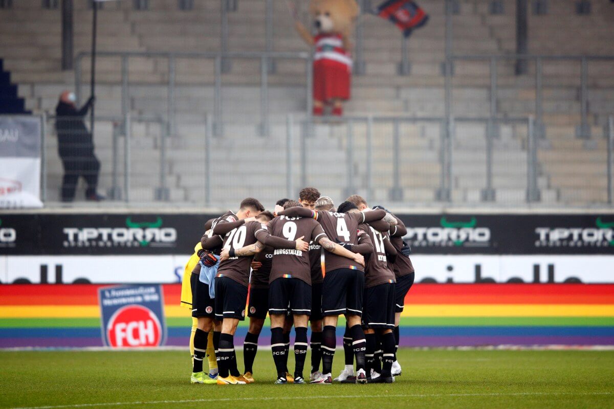 Spielerkreis des FC St. Pauli vor dem Spiel beim 1. FC Heidenheim am 31.01.2021, im Hintergrund eine Werbebande in Regenbogenfarben und das Heidenheimer Maskottchen auf der Tribüne. // (c) Adam Pretty / Getty Images via OneFootball