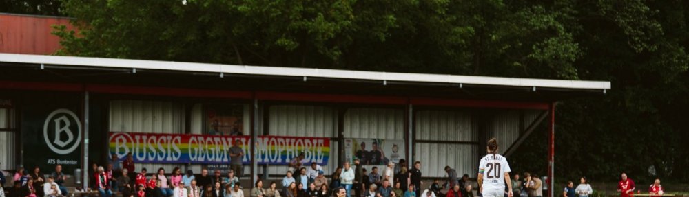 Gianna Nicoleit (FC St. Pauli) in der Hocke nach dem Spiel beim ATS Buntentor. Im Hintergrund ein "Bussies gegen Homophobie"-Banner. // (c) @eddy.photogr