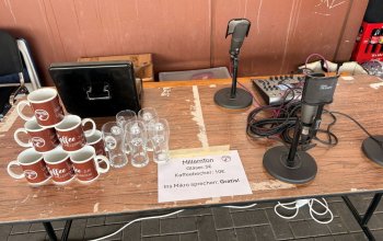 Aufnahmetisch inklusive Mikrofon, Kaffeebechern und Gläsern.