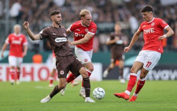 ESSEN, GERMANY - AUGUST 23: Tony Menzel of RW Essen (C) challenges Branimir Hrgota of FC St. Pauli (L) during the DFB Cup 2026/27 match between Rot-Weiss Essen and St. Pauli at Stadion an der Hafenstrasse on August 23, 2026 in Essen, Germany. (Photo by Christof Koepsel/Getty Images)