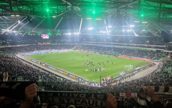 Blick aus dem Gästeblock in Hannover auf das Spielfeld nach dem Abpfiff der Begegnung, die Spieler stehen vor dem Block, Fans halten Schals hoch